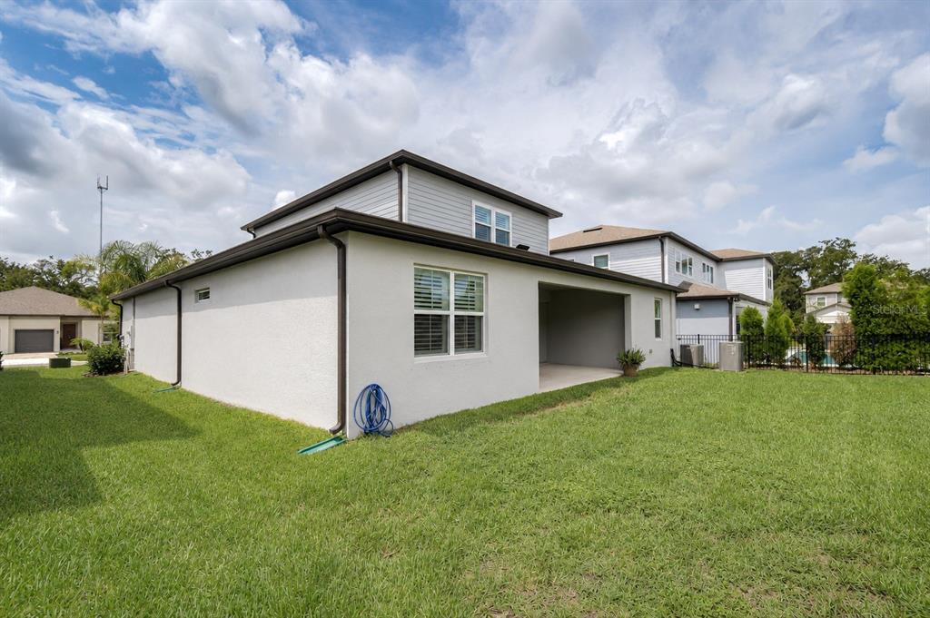 A view of the back of a two-story house with a covered patio and lawn — 13857 SHARP HAWK DRIVE, RIVERVIEW, FL