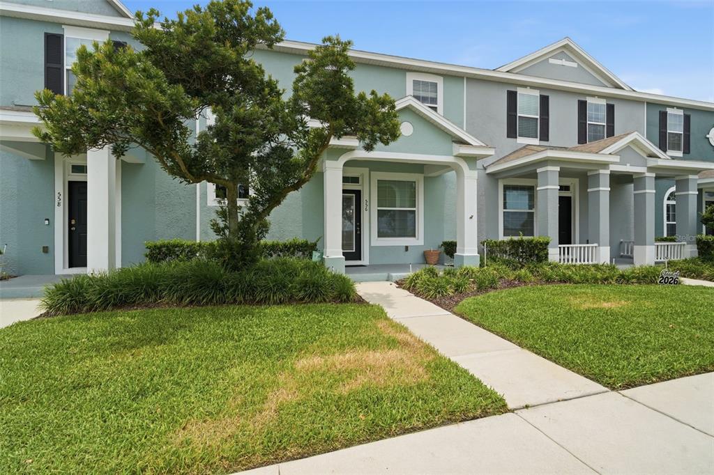 A row of light blue townhouses with covered front porches and small front lawns — 556 JUNIPER SPRINGS DRIVE, GROVELAND, FL