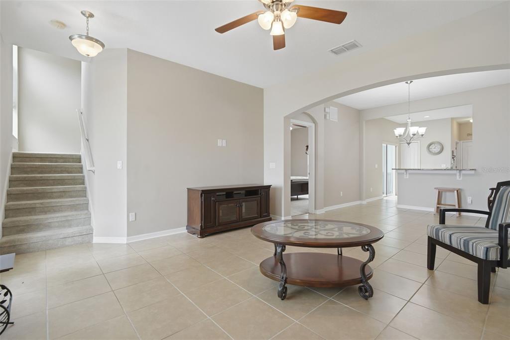 A living room with tile flooring, a ceiling fan, a staircase, and an arched entryway — 556 JUNIPER SPRINGS DRIVE, GROVELAND, FL