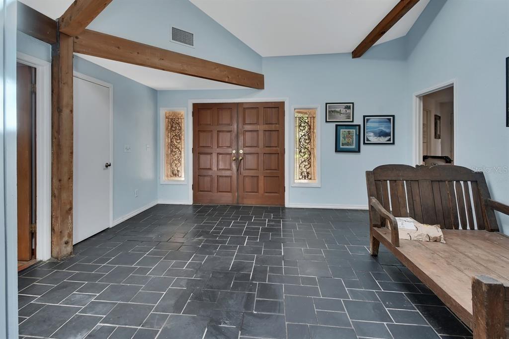 An entryway with slate tile flooring, light blue walls, exposed wooden beams, and double doors — 175 BAYWOOD DRIVE, OAK HILL, FL