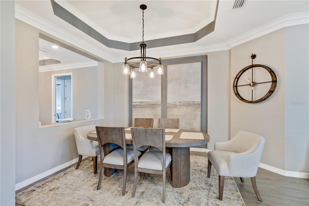 A dining room features a wooden table, six chairs, a chandelier, and a wall clock — 12584 WELLEN GOLF STREET, VENICE, FL