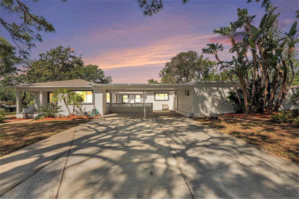 A white single-story house with a large concrete driveway and a covered carport — 4925 ALCAZAR WAY S, ST PETERSBURG, FL