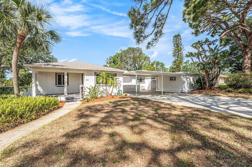 A single-story house with a white exterior, a front porch, and an attached carport — 4925 ALCAZAR WAY S, ST PETERSBURG, FL