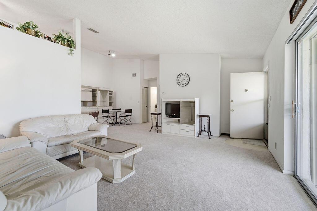 A living room with white carpet, a white sofa, a coffee table, and a television console — 6519 Chasewood Drive, Jupiter FL 33458, JUPITER, FL