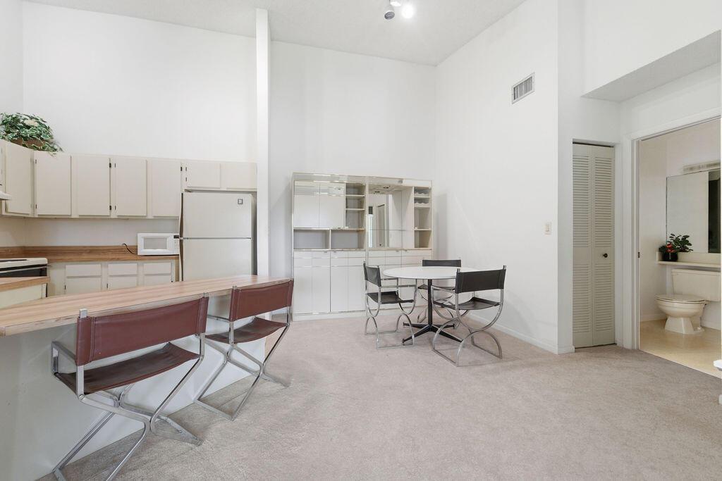 A kitchen and dining area with white cabinets, a breakfast bar, and carpeted flooring — 6519 Chasewood Drive, Jupiter FL 33458, JUPITER, FL