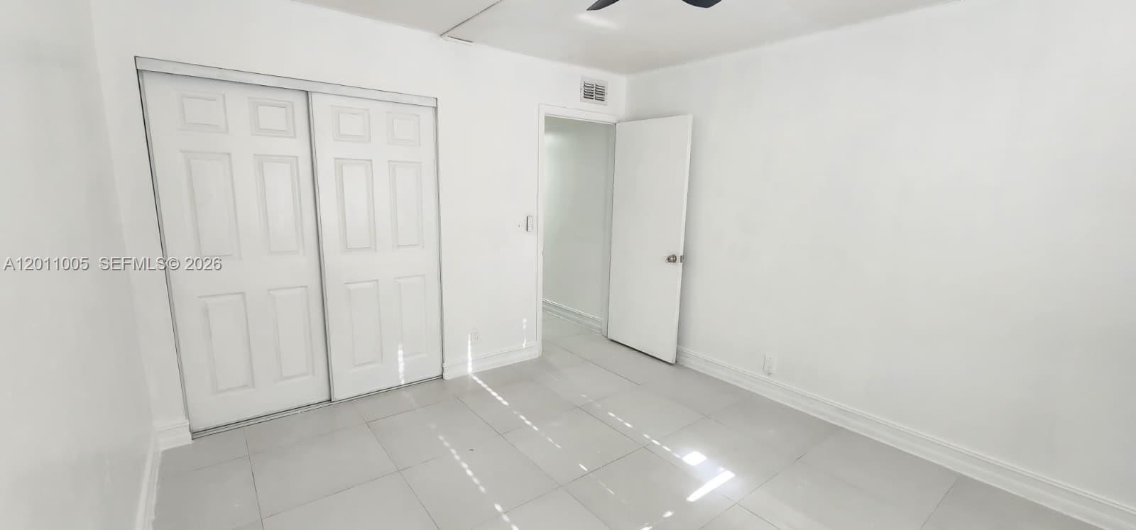 A room with white walls, light-colored tile flooring, a sliding closet, and an open doorway — 1020 NW 80th Ave # 203, Margate FL 33063, MARGATE, FL