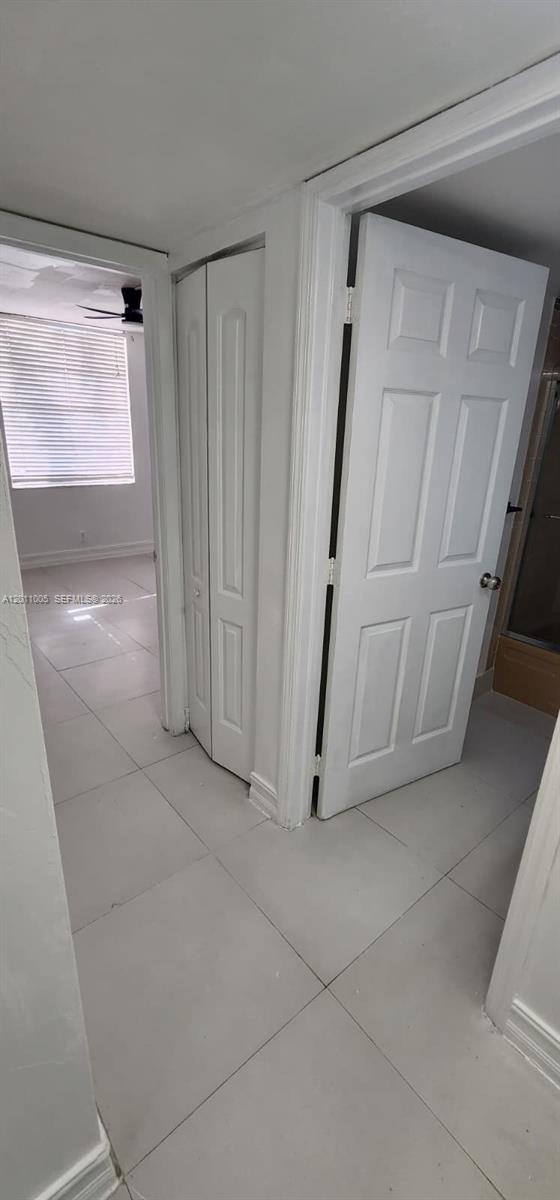 A hallway with white tile floors leads to a room with a window and blinds — 1020 NW 80th Ave # 203, Margate FL 33063, MARGATE, FL