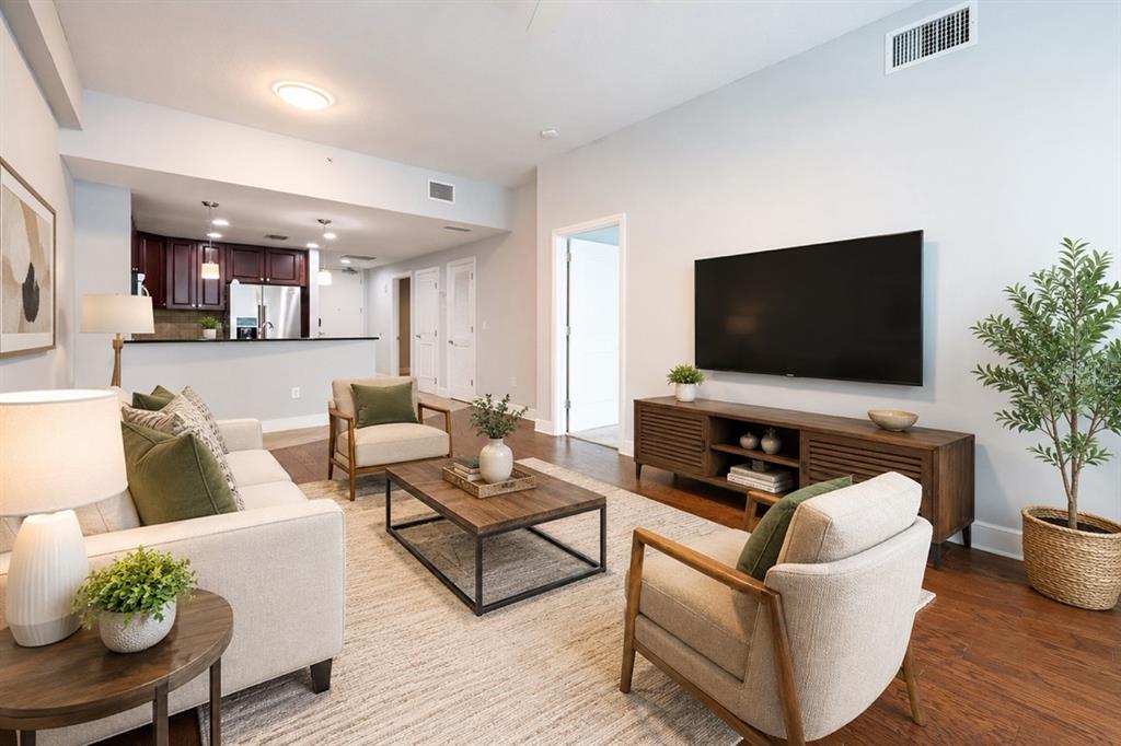 A living room with a television, wooden media console, sofa, armchairs, and an open kitchen — 101 S EOLA DRIVE UNIT 614, ORLANDO, FL