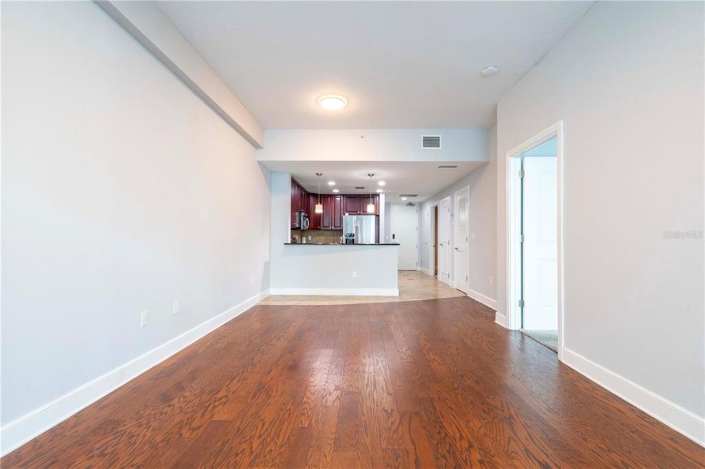 An interior view of a living area with hardwood floors leading to an open kitchen — 101 S EOLA DRIVE UNIT 614, ORLANDO, FL