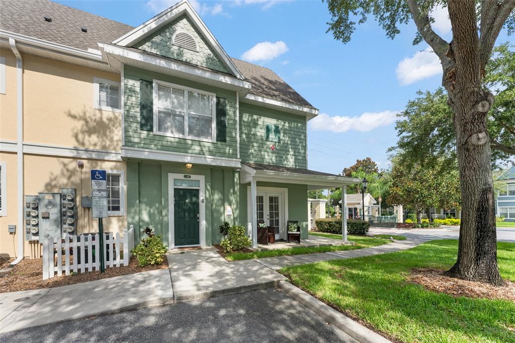 A two-story green townhouse exterior features a front porch, a white fence, and landscaping — 4000 VENETIAN BAY DRIVE UNIT 107, KISSIMMEE, FL