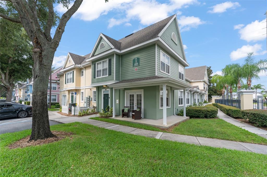 A green two-story building with a covered porch and a sidewalk in the foreground — 4000 VENETIAN BAY DRIVE UNIT 107, KISSIMMEE, FL