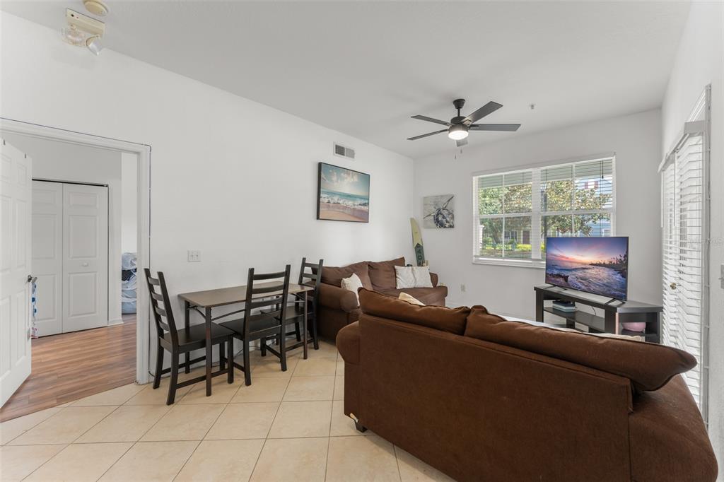 A living room and dining area with brown sofas, a dining table, and tile flooring — 4000 VENETIAN BAY DRIVE UNIT 107, KISSIMMEE, FL