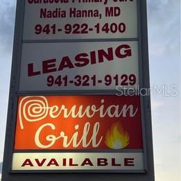 A multi-tenant commercial sign displays business names, contact numbers, and leasing information — 3131 CLARK ROAD UNIT 101, SARASOTA, FL