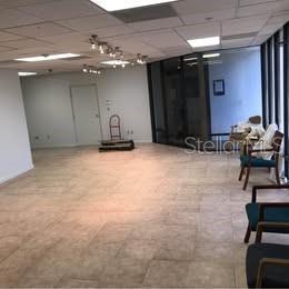 An empty office waiting area features light-colored tile flooring and a glass-walled conference room — 3131 CLARK ROAD UNIT 101, SARASOTA, FL