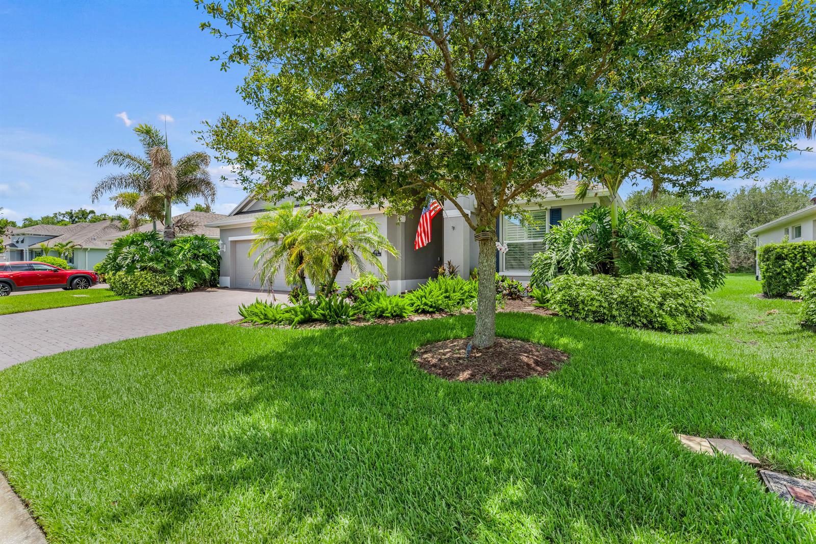 A single-story house with a paved driveway, a large tree, and lush landscaping in front — 1573 Segovia Circle, Vero Beach FL 32966, VERO BEACH, FL