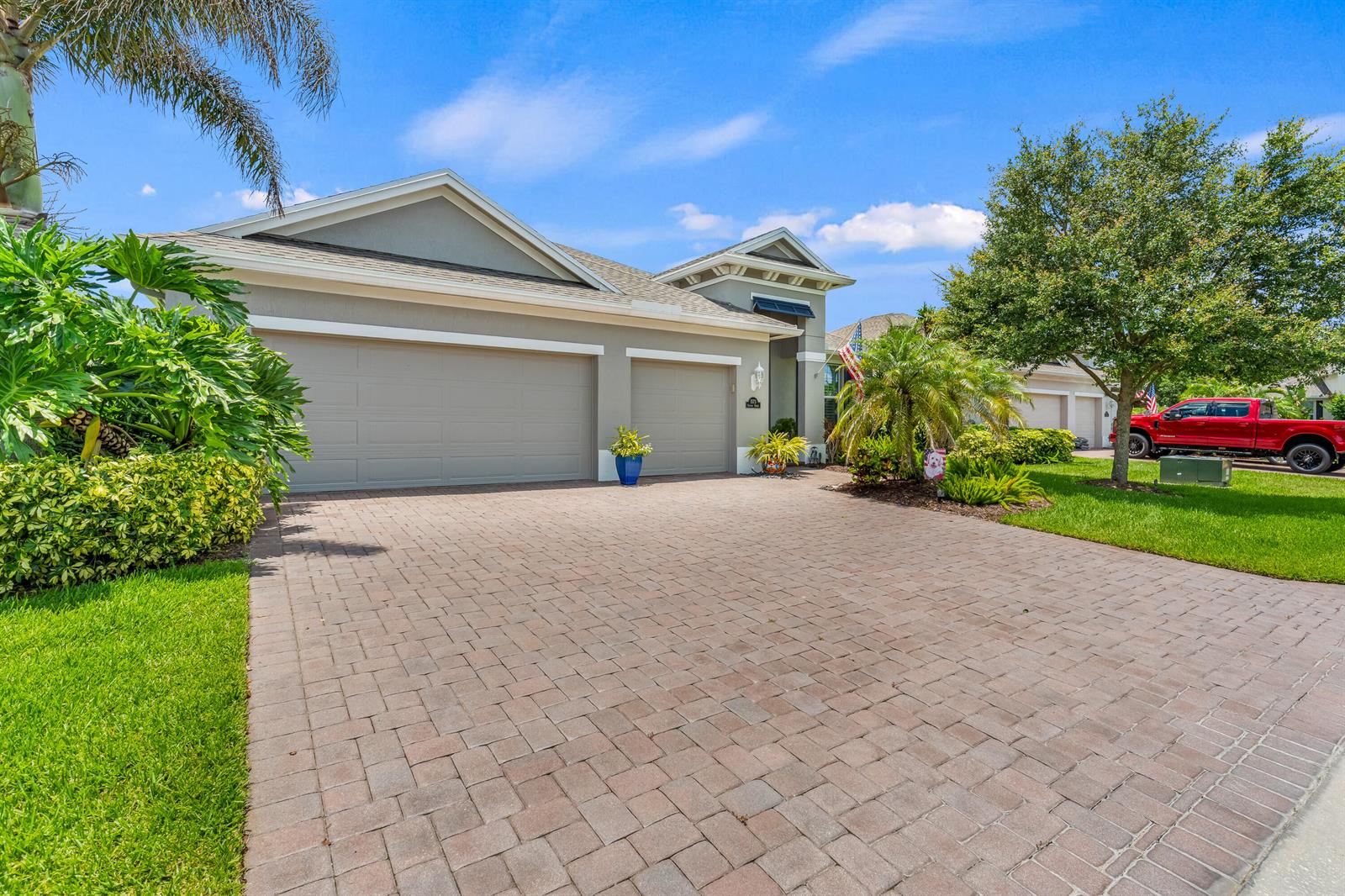 A single-story house with a paved driveway, a three-car garage, and lush landscaping — 1573 Segovia Circle, Vero Beach FL 32966, VERO BEACH, FL