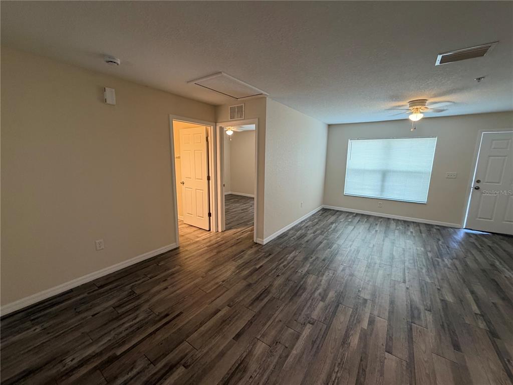 An interior view of a living area featuring wood-look flooring and two open doorways — 8532 JUNIPER ROAD UNIT 2, OCALA, FL