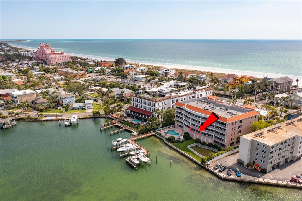 An aerial view shows a waterfront condominium complex with a pool and boat docks — 3805 GULF BOULEVARD UNIT 203, ST PETE BEACH, FL