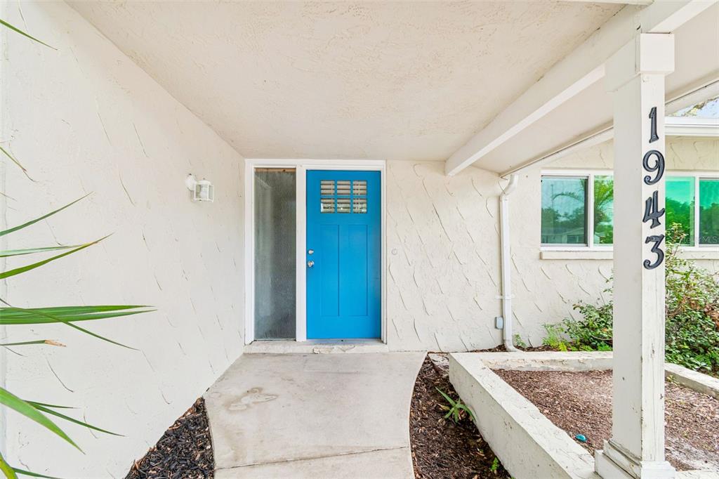 A view through a blue front door into an open-concept living area with wood flooring — 1943 BARBARA AVENUE, CLEARWATER, FL