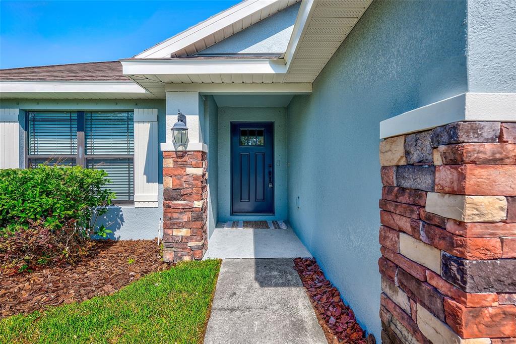 A blue front door is framed by stone pillars and a covered entryway — 12220 LEGACY BRIGHT STREET, RIVERVIEW, FL