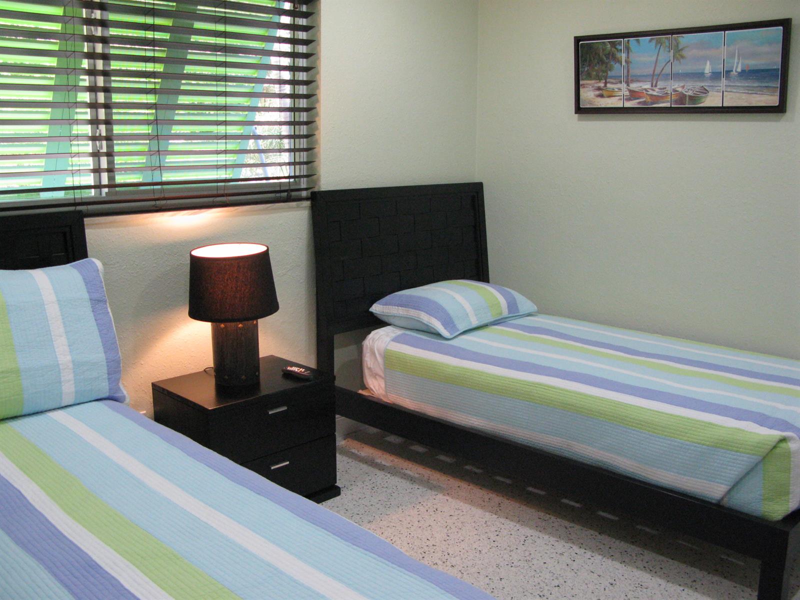 A bedroom features two twin beds with striped bedding, a nightstand with a lamp, and artwork — 13767 Oleander Avenue E, Juno Beach FL 33408, JUNO BEACH, FL