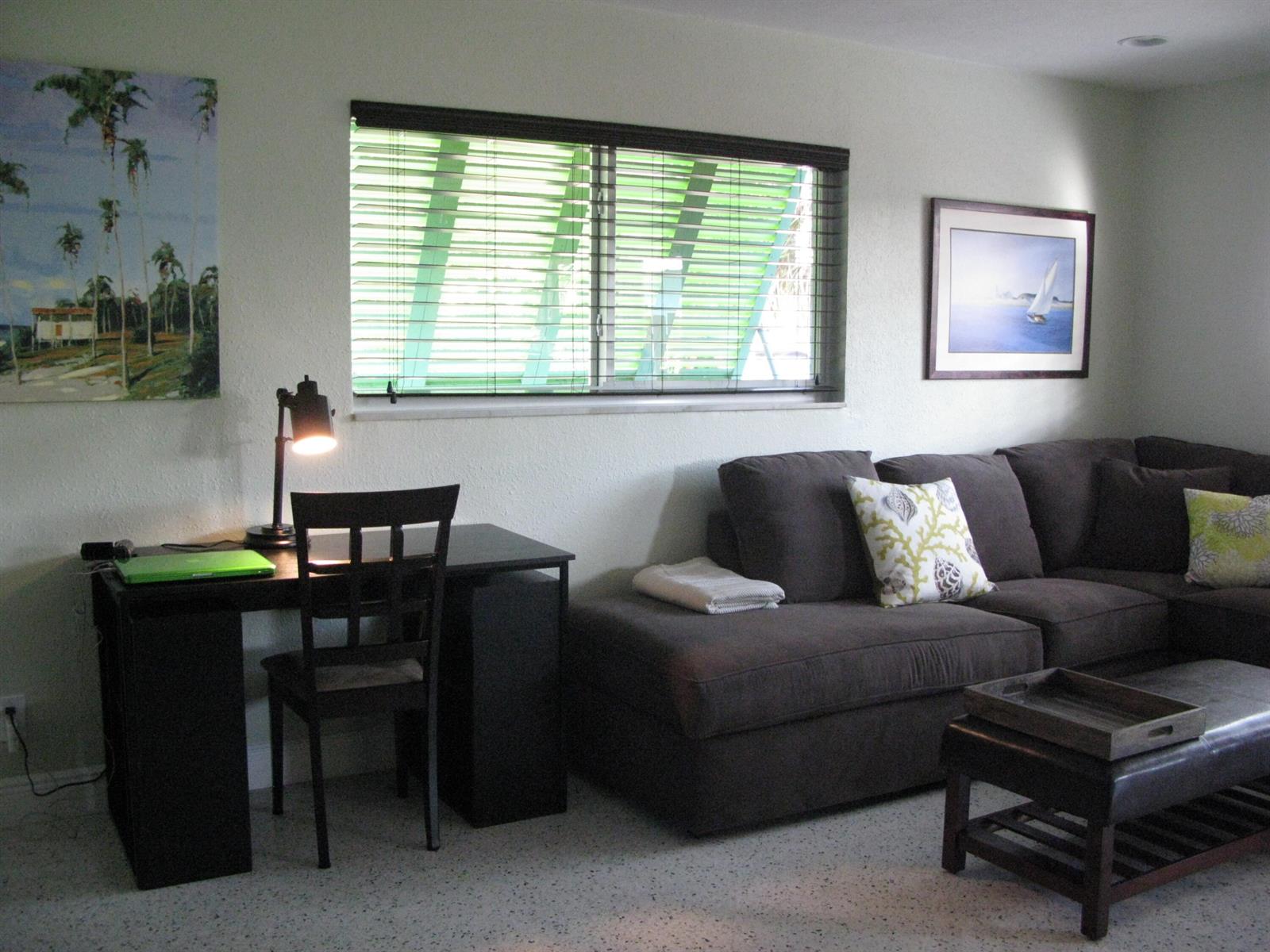 A living room features a dark desk, a sectional sofa, and a window with blinds — 13767 Oleander Avenue E, Juno Beach FL 33408, JUNO BEACH, FL