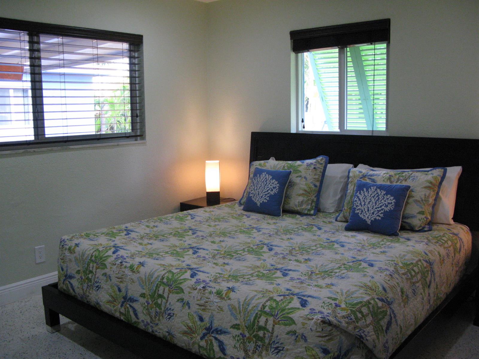 A bedroom features a bed with a tropical print quilt and two windows with blinds — 13767 Oleander Avenue E, Juno Beach FL 33408, JUNO BEACH, FL