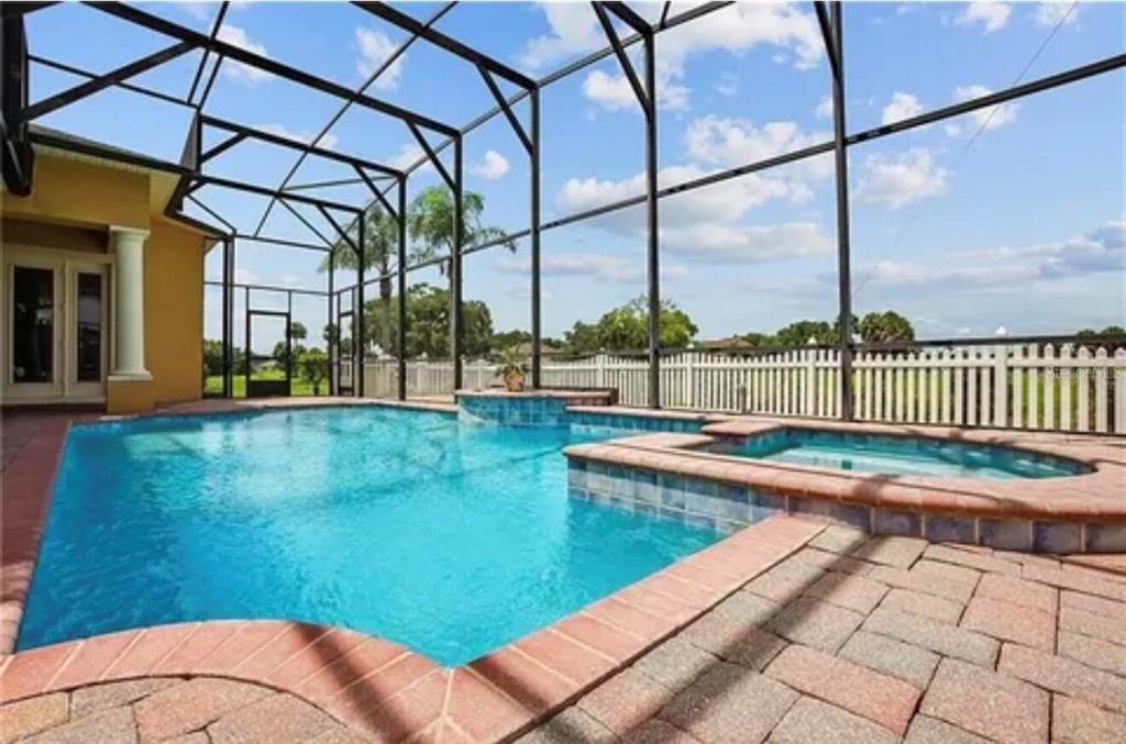 A swimming pool and spa are enclosed within a screened lanai with brick paver decking — 2120 BUNKER VIEW COURT, KISSIMMEE, FL