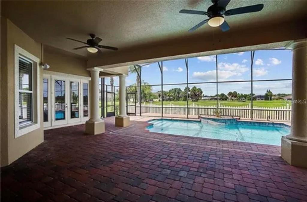 A covered brick patio overlooks a screened-in swimming pool and a grassy backyard — 2120 BUNKER VIEW COURT, KISSIMMEE, FL
