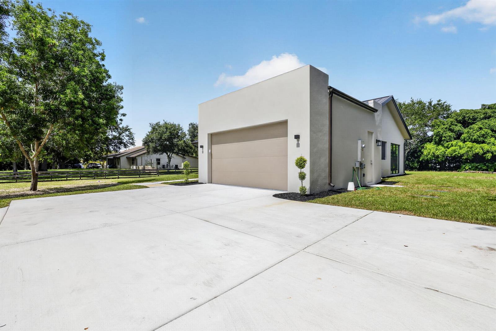 A modern, light-colored detached garage with a concrete driveway sits on a grassy lot — 5356 Colbright Road, Lake Worth FL 33467, LAKE WORTH, FL