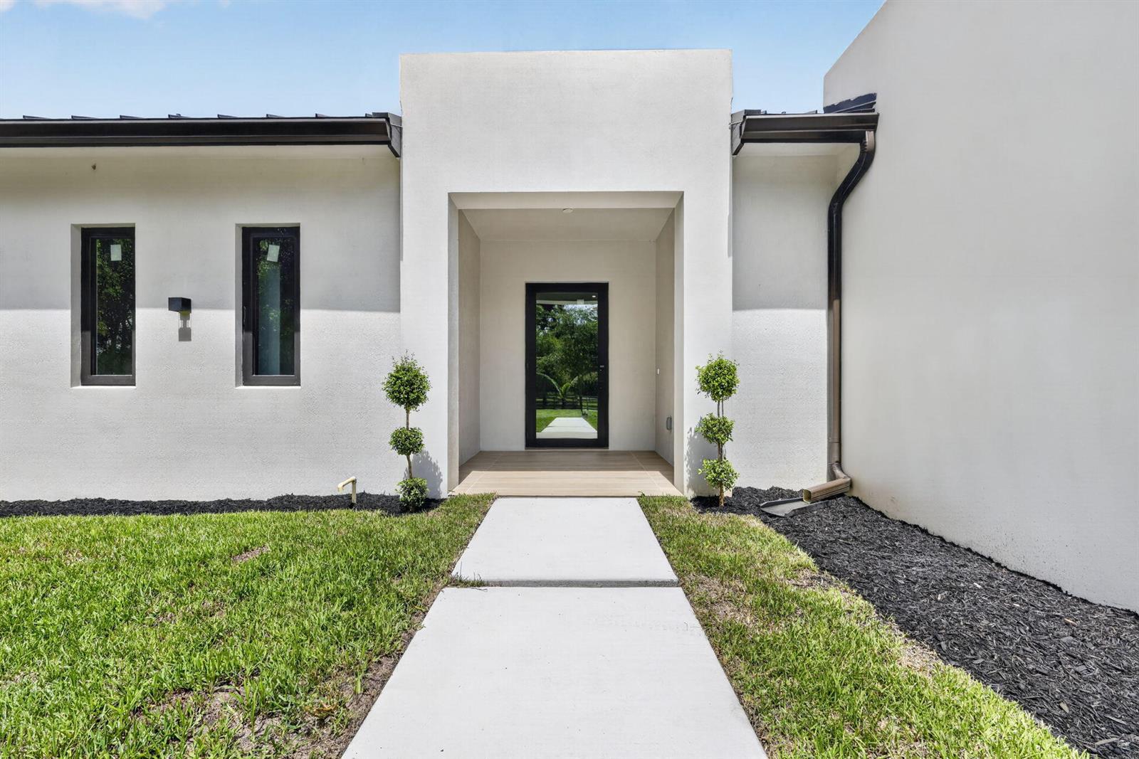 A modern white stucco house exterior features a recessed entryway with a glass front door — 5356 Colbright Road, Lake Worth FL 33467, LAKE WORTH, FL