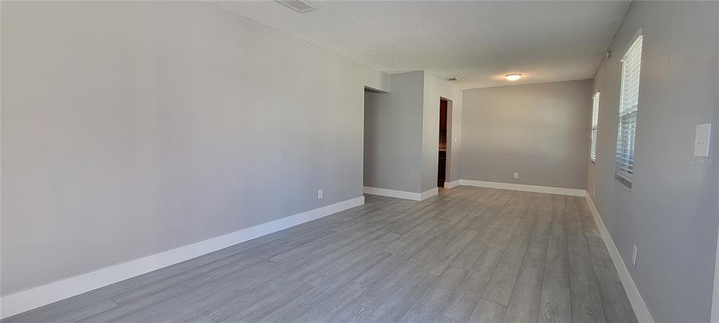 An empty room with gray walls, light wood-look flooring, and white baseboards — 6627 S WEST SHORE BOULEVARD, TAMPA, FL