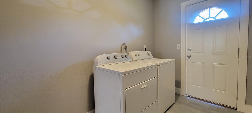 A laundry room features a white washer and dryer next to an exterior door — 6627 S WEST SHORE BOULEVARD, TAMPA, FL