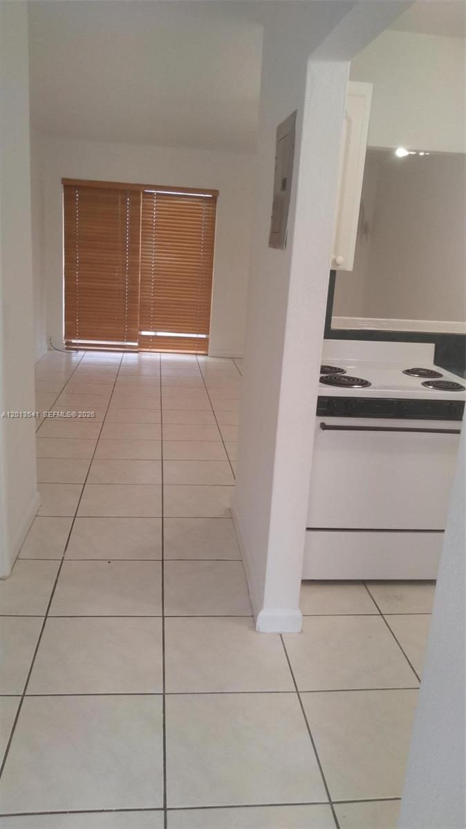 A tiled kitchen area leads to a living space with sliding glass doors and blinds — 1441 Lincoln Rd # 414, Miami Beach FL 33139, MIAMI BEACH, FL