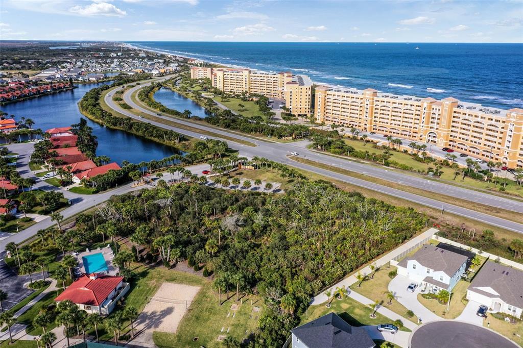 An aerial view shows a coastal landscape with residential buildings, a road, and the ocean — 6700 N OCEAN SHORE BOULEVARD, PALM COAST, FL
