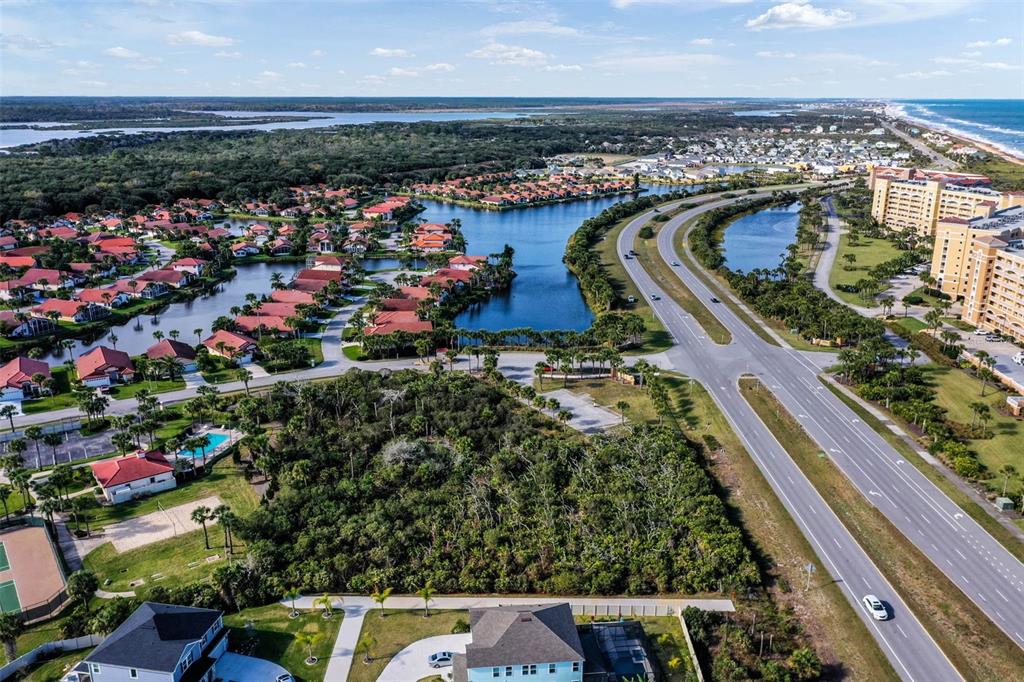 An aerial view shows a residential neighborhood with a lake, dense vegetation, and a highway — 6700 N OCEAN SHORE BOULEVARD, PALM COAST, FL