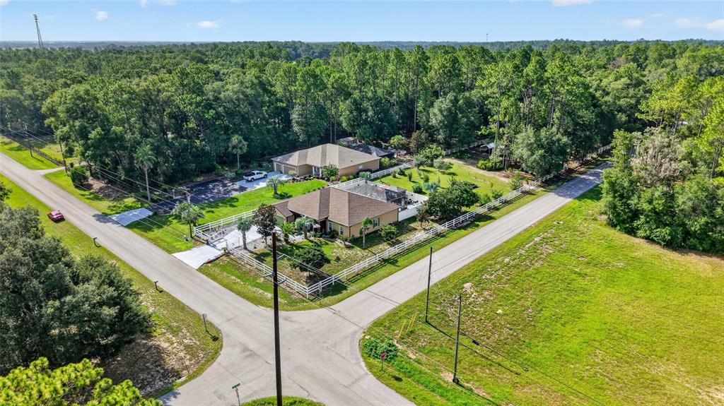 An aerial view shows two suburban houses situated on a corner lot surrounded by trees — 20096 SW 59TH LANE, DUNNELLON, FL