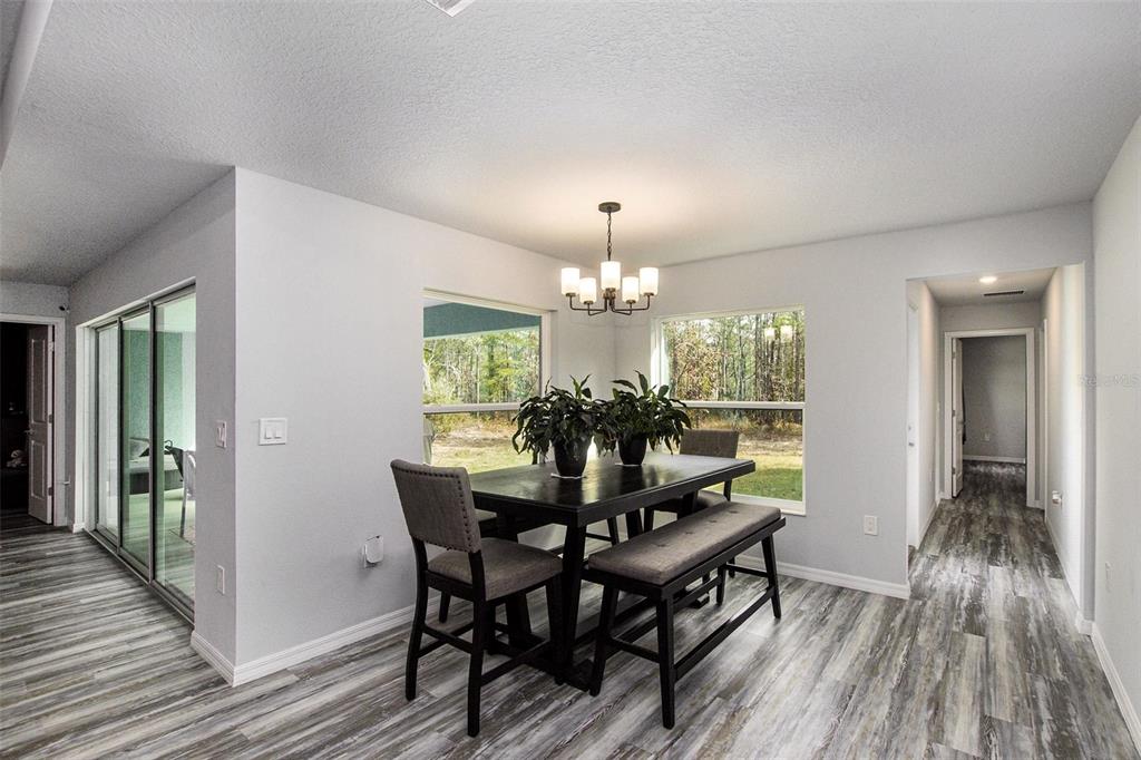 A dining area with a dark table, chairs, bench, chandelier, and wood-look flooring — 128 CYPRESS BOULEVARD E, HOMOSASSA, FL