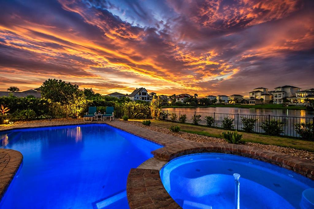 A backyard swimming pool and hot tub overlook a lake at sunset — 7 HAMMOCK BEACH CIRCLE S, PALM COAST, FL