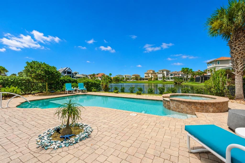 A swimming pool and hot tub sit on a paved patio overlooking a lake — 7 HAMMOCK BEACH CIRCLE S, PALM COAST, FL