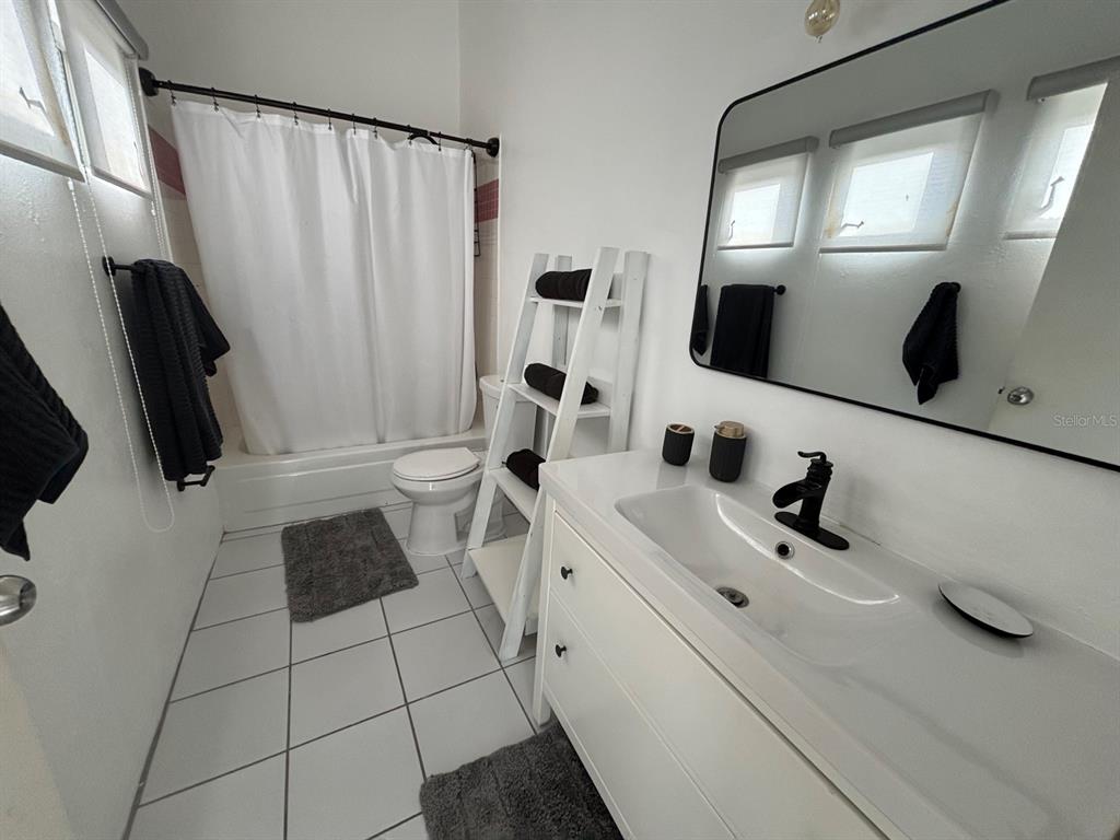 A bathroom features a white vanity, a toilet, a shower-tub combo, and a ladder shelf — 150 PALMAS DRIVE UNIT 118, HUMACAO, PR