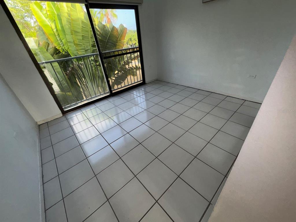 An empty room features white tile flooring, plain walls, and a sliding glass door balcony — 150 PALMAS DRIVE UNIT 118, HUMACAO, PR