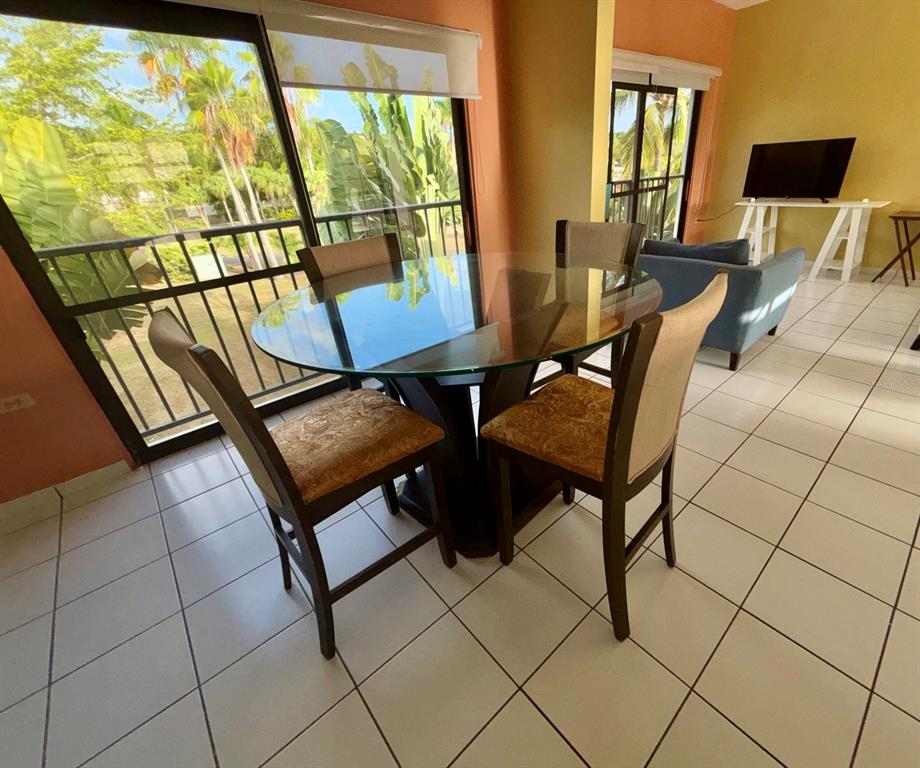 A dining area features a glass-topped table with four chairs and large sliding glass doors — 150 PALMAS DRIVE UNIT 118, HUMACAO, PR