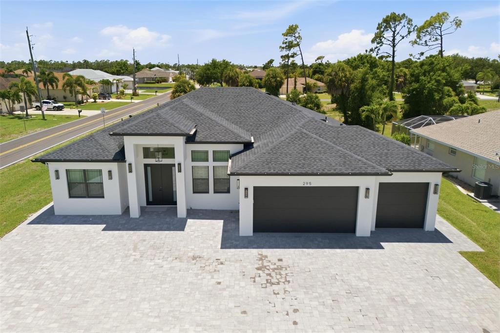 An aerial view of a modern single-story house with a dark roof and paved driveway — 295 WHITE MARSH LANE, ROTONDA WEST, FL