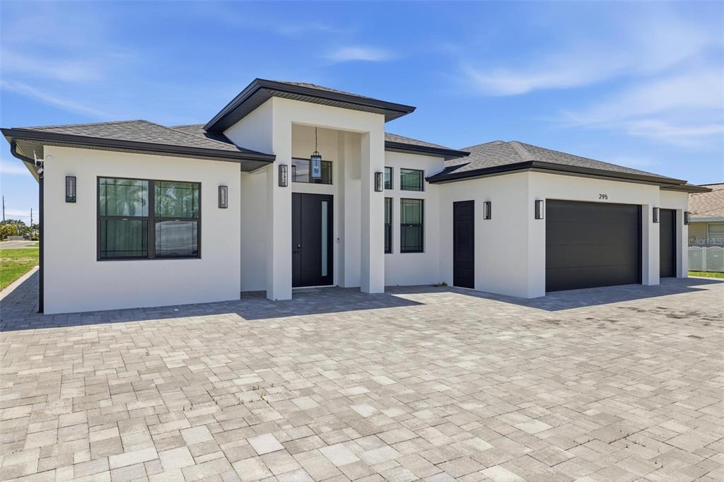A modern single-story house with a white stucco exterior, dark trim, and a paved driveway — 295 WHITE MARSH LANE, ROTONDA WEST, FL