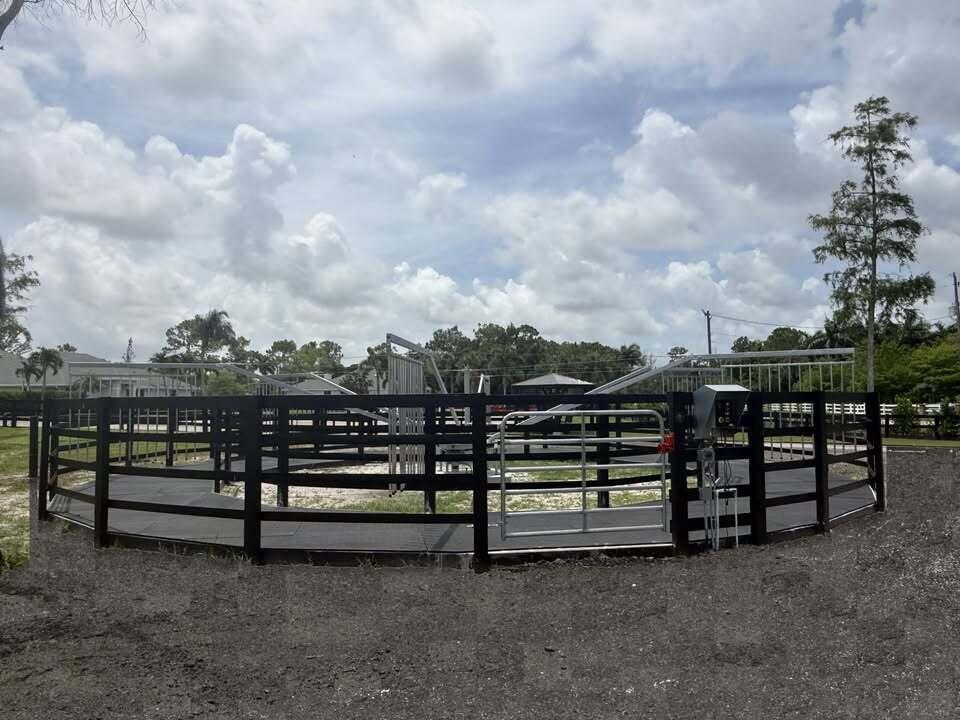 An outdoor horse walker enclosed by a black wooden fence under a cloudy sky — 6600 Duckweed Road, Wellington FL 33449, WELLINGTON, FL