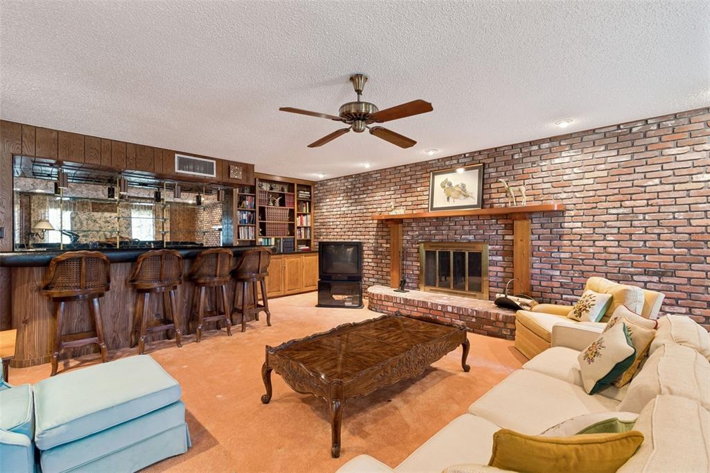 A living room features a brick fireplace, a built-in bar, and a wooden coffee table — 29244 WHIPPORWILL LANE, WESLEY CHAPEL, FL