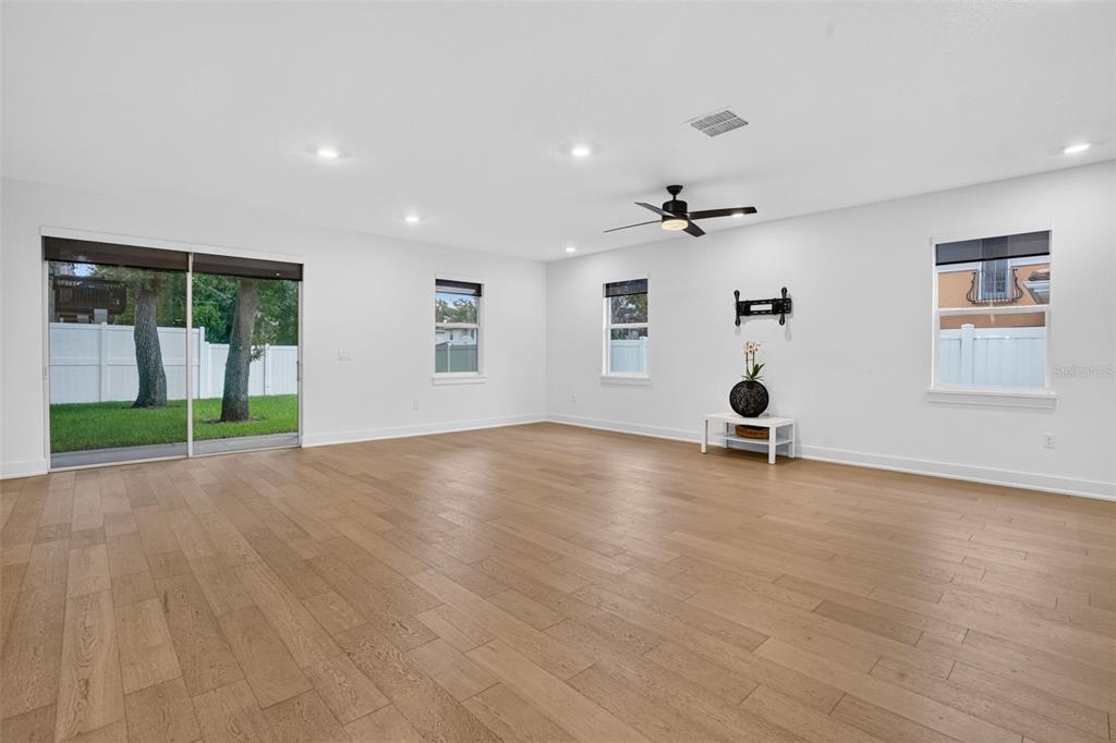 A spacious living room features light wood flooring, white walls, recessed lighting, and sliding glass doors — 5818 1/2 S 6TH STREET, TAMPA, FL