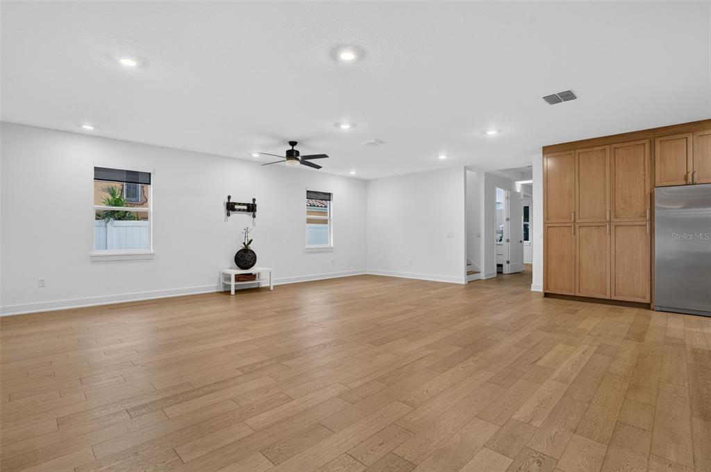 A spacious, open-concept room features light wood flooring, white walls, recessed lighting, and wooden cabinetry — 5818 1/2 S 6TH STREET, TAMPA, FL