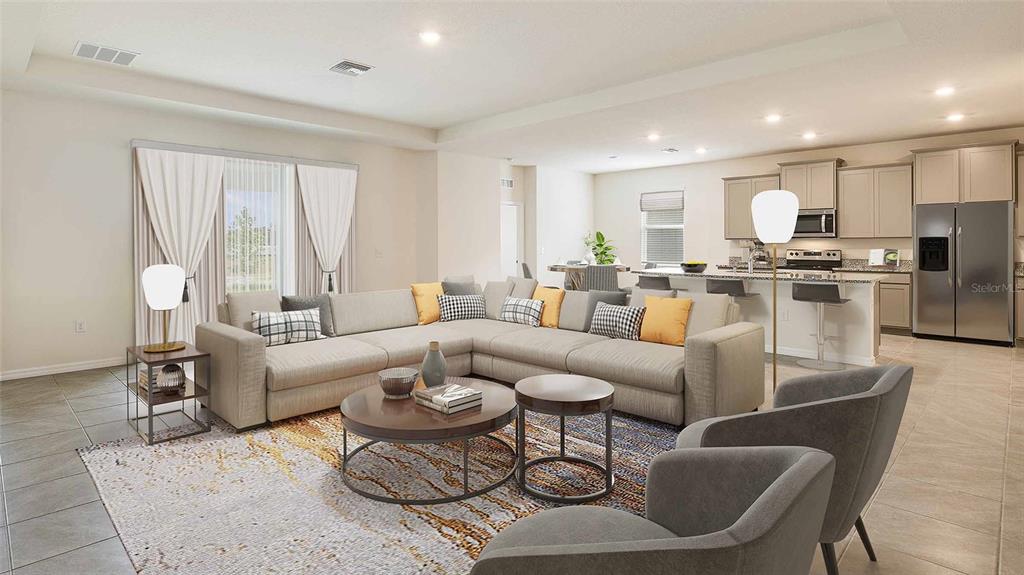 A spacious open-concept living room features a large sectional sofa, area rug, and modern kitchen — 304 158TH STREET E, BRADENTON, FL
